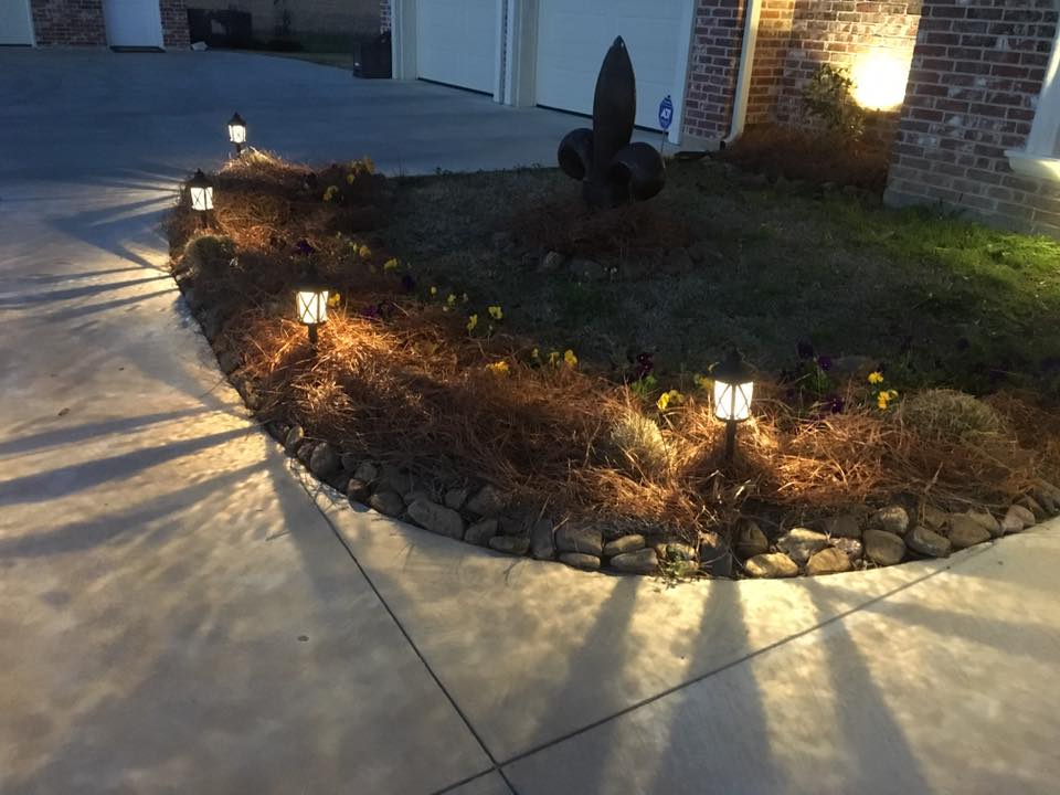 landscape lighting complimented by pansies and brown creek rock border