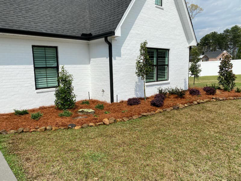 Arkansas stones and holly bushes planted in creative landscape design
